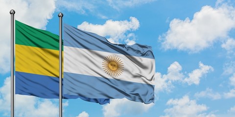 Gabon and Argentina flag waving in the wind against white cloudy blue sky together. Diplomacy...