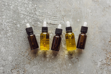top view of bottles with natural serum near fir branches on grey stone surface
