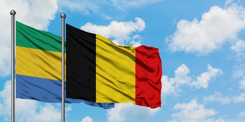 Gabon and Belgium flag waving in the wind against white cloudy blue sky together. Diplomacy...
