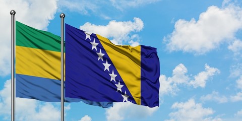 Gabon and Bosnia Herzegovina flag waving in the wind against white cloudy blue sky together....