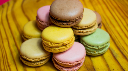 Colored macarons isolated on wooden dish, typical French dish