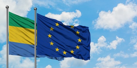 Gabon and European Union flag waving in the wind against white cloudy blue sky together. Diplomacy...