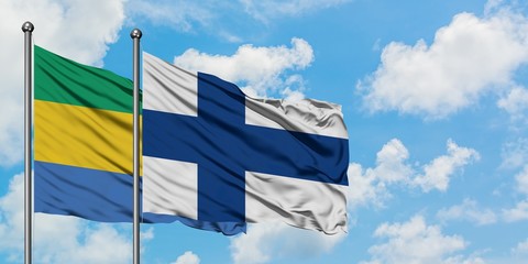 Gabon and Finland flag waving in the wind against white cloudy blue sky together. Diplomacy...