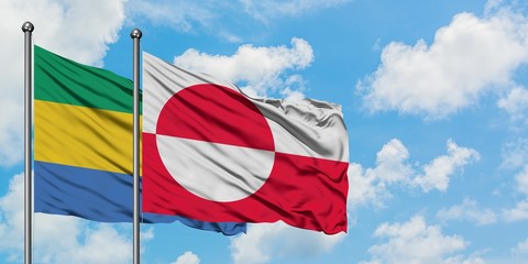 Gabon and Greenland flag waving in the wind against white cloudy blue sky together. Diplomacy...