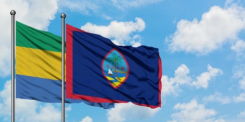 Gabon and Guam flag waving in the wind against white cloudy blue sky together. Diplomacy concept, international relations.