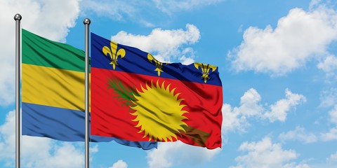 Gabon and Guadeloupe flag waving in the wind against white cloudy blue sky together. Diplomacy concept, international relations.