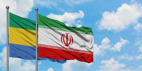 Gabon and Iran flag waving in the wind against white cloudy blue sky together. Diplomacy concept,...