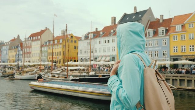 A woman strolls along the Nyhavn canal, against the background of famous colorful houses.