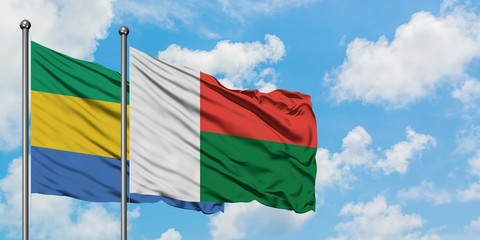 Gabon and Madagascar flag waving in the wind against white cloudy blue sky together. Diplomacy concept, international relations.