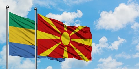 Gabon and Macedonia flag waving in the wind against white cloudy blue sky together. Diplomacy...