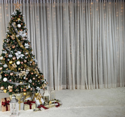 Christmas tree with colorful baubles and gift boxes over white curtain