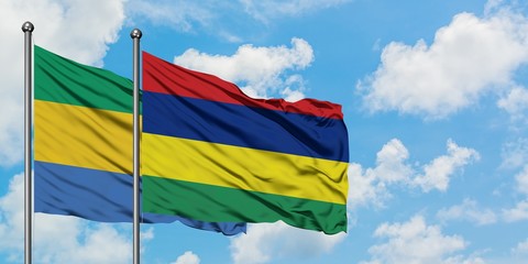 Gabon and Mauritius flag waving in the wind against white cloudy blue sky together. Diplomacy concept, international relations.