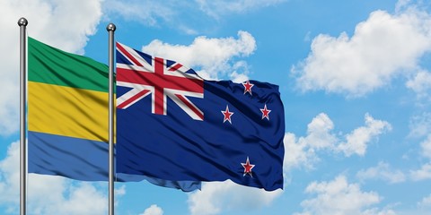 Gabon and New Zealand flag waving in the wind against white cloudy blue sky together. Diplomacy...