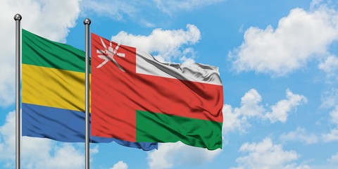 Gabon and Oman flag waving in the wind against white cloudy blue sky together. Diplomacy concept,...