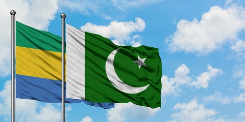 Gabon and Pakistan flag waving in the wind against white cloudy blue sky together. Diplomacy...