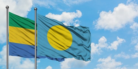 Gabon and Palau flag waving in the wind against white cloudy blue sky together. Diplomacy concept,...