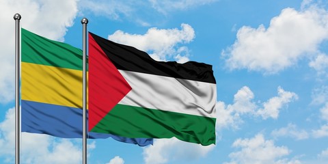 Gabon and Palestine flag waving in the wind against white cloudy blue sky together. Diplomacy...
