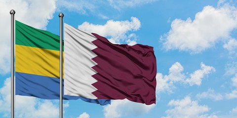 Gabon and Qatar flag waving in the wind against white cloudy blue sky together. Diplomacy concept, international relations.