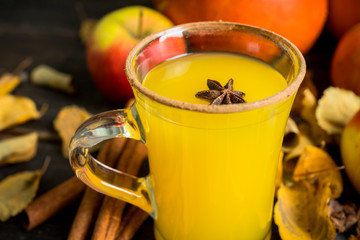 Autumn hot and spicy drink with pumpkin and orange juice on the rustic background. Selective focus....