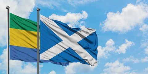 Gabon and Scotland flag waving in the wind against white cloudy blue sky together. Diplomacy...