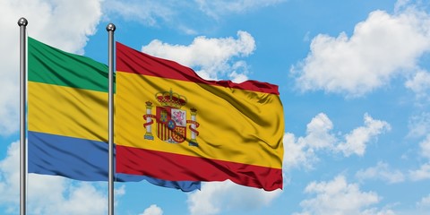 Gabon and Spain flag waving in the wind against white cloudy blue sky together. Diplomacy concept, international relations.