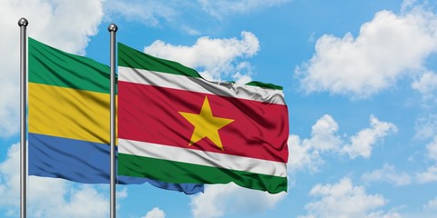 Gabon and Suriname flag waving in the wind against white cloudy blue sky together. Diplomacy concept, international relations.