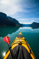 gelbes Kajak mit paddel auf einem Fjord, Berge im Hintergrund - obrazy, fototapety, plakaty