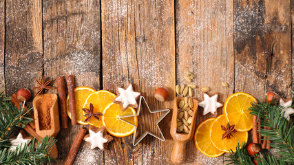 christmas decoration on wooden background with spices, orange, biscuit