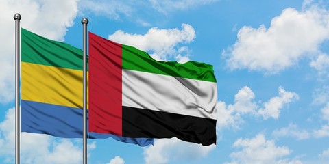 Gabon and United Arab Emirates flag waving in the wind against white cloudy blue sky together....
