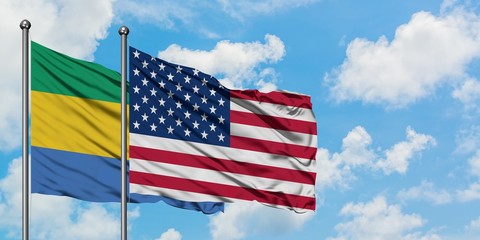 Gabon and United States flag waving in the wind against white cloudy blue sky together. Diplomacy concept, international relations.