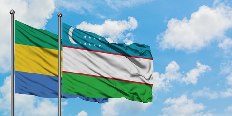 Gabon and Uzbekistan flag waving in the wind against white cloudy blue sky together. Diplomacy...