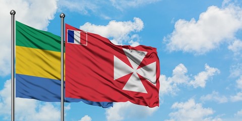 Gabon and Wallis And Futuna flag waving in the wind against white cloudy blue sky together....