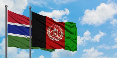 Gambia and Afghanistan flag waving in the wind against white cloudy blue sky together. Diplomacy...