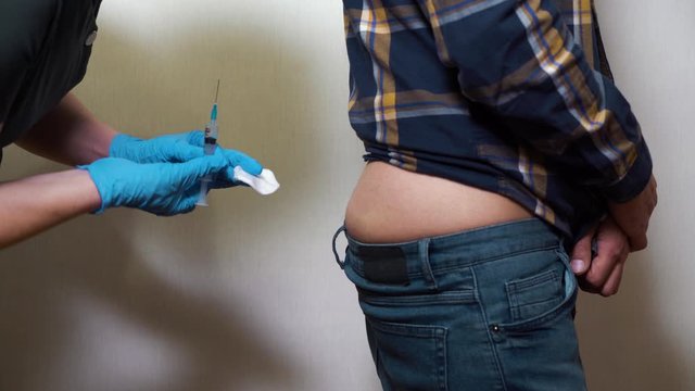 Nurse making buttock injection for male patient