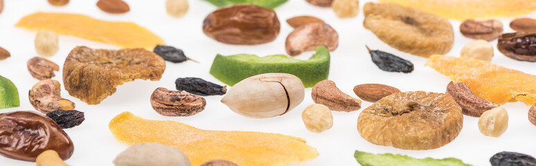 close up view of tasty assorted nuts, dried fruits and candied fruit isolated on white, panoramic shot