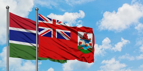 Gambia and Bermuda flag waving in the wind against white cloudy blue sky together. Diplomacy...