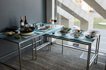 beverages and dishes served at glass tables in restaurant for stand-up meal