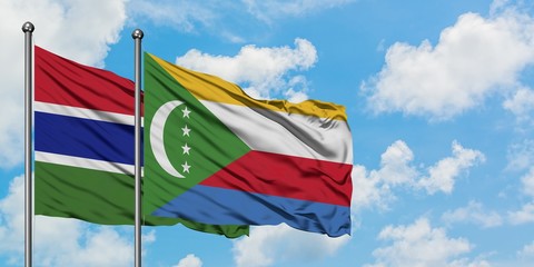 Gambia and Comoros flag waving in the wind against white cloudy blue sky together. Diplomacy...