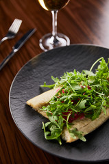 selective focus of tasty restaurant fish steak with lime and arugula on wooden table near cutlery and wine