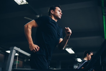 authentic image of attractive man running on the treadmill in the gym. concept of weight los and active living.