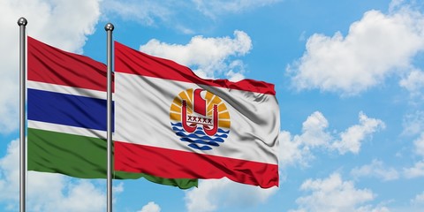 Gambia and French Polynesia flag waving in the wind against white cloudy blue sky together. Diplomacy concept, international relations.