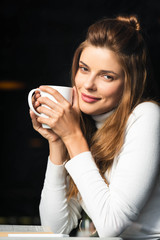 attractive happy woman holding cup of coffee in cafe