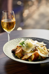 tasty Caesar salad with Parmesan slices served on plate with white wine in sunlight