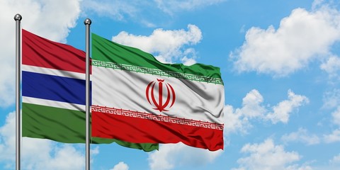 Gambia and Iran flag waving in the wind against white cloudy blue sky together. Diplomacy concept,...