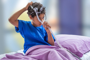 Child suffering from Sleep Apnea, wearing a respiratory mask.
