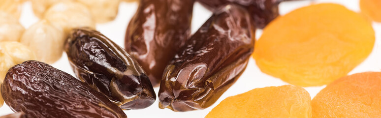 close up view of dried apricots, dates and hazelnut isolated on white, panoramic shot