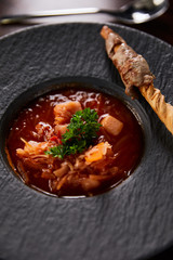 traditional ukrainian borscht garnished with parsley in black plate