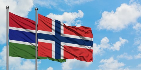 Gambia and Norway flag waving in the wind against white cloudy blue sky together. Diplomacy concept, international relations.