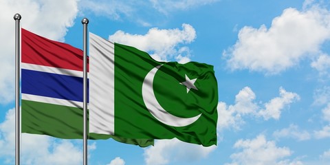 Gambia and Pakistan flag waving in the wind against white cloudy blue sky together. Diplomacy...