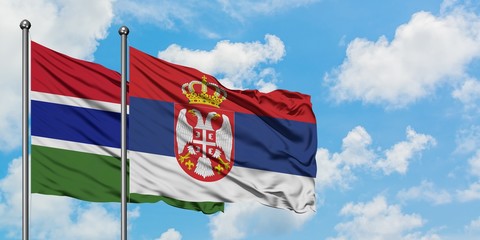 Gambia and Serbia flag waving in the wind against white cloudy blue sky together. Diplomacy concept, international relations.